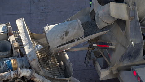 close-up eines betonmischerfahrzeugs, der die frische ladung in die rückseite eines boompumpenfahrzeugs in langsamer bewegung abwerft