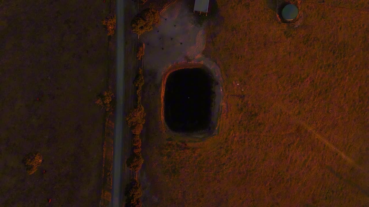 Panoramica aerea di una proprietà rurale e di una strada sterrata nella Hindmarsh Valley al tramonto, stagno con stormo di uccelli, ripresa aerea dall'alto con drone