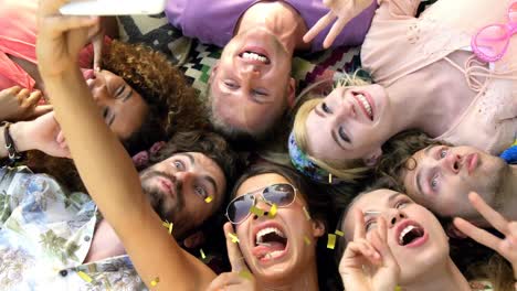 animation of confetti falling over female friends lying on grass taking selfies at summer camp