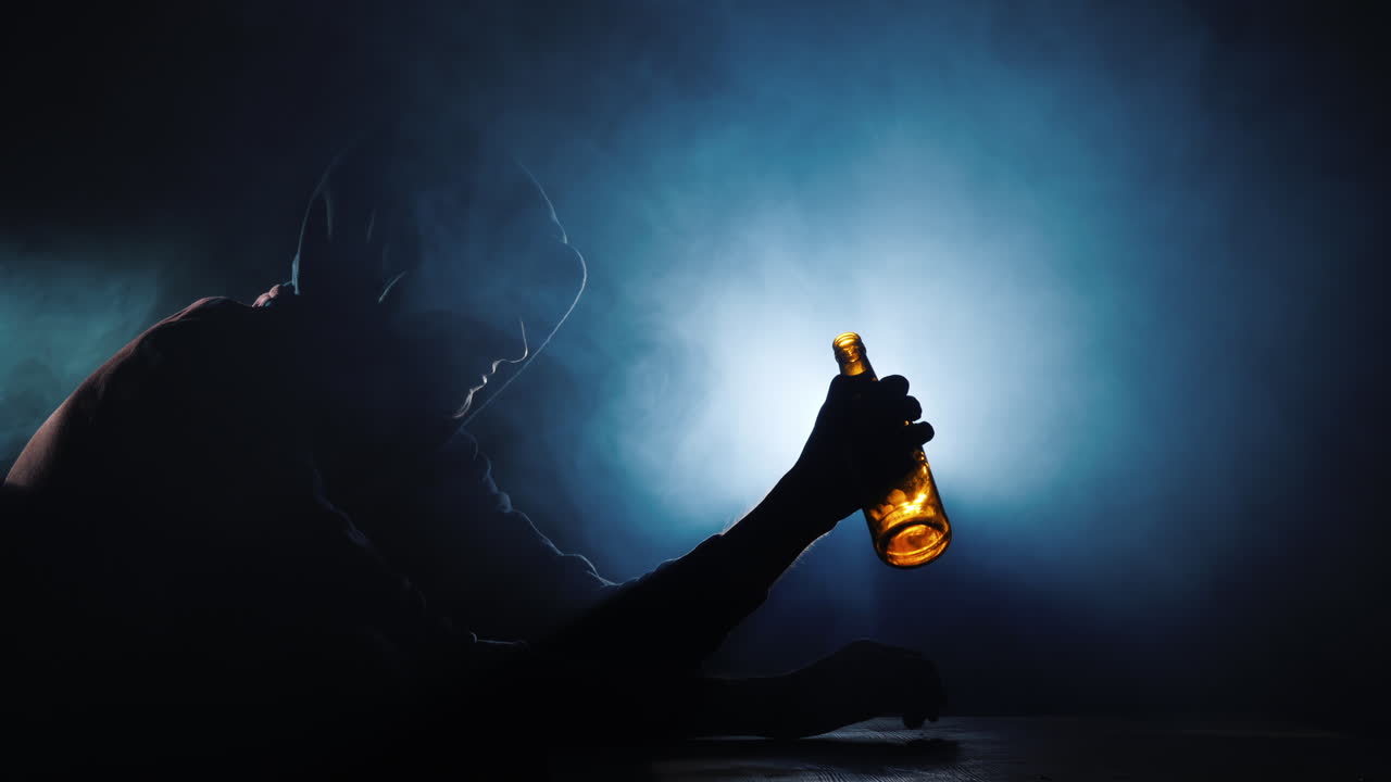 빈 술병을 손에 들고 앉아 있는 남자의 실루엣