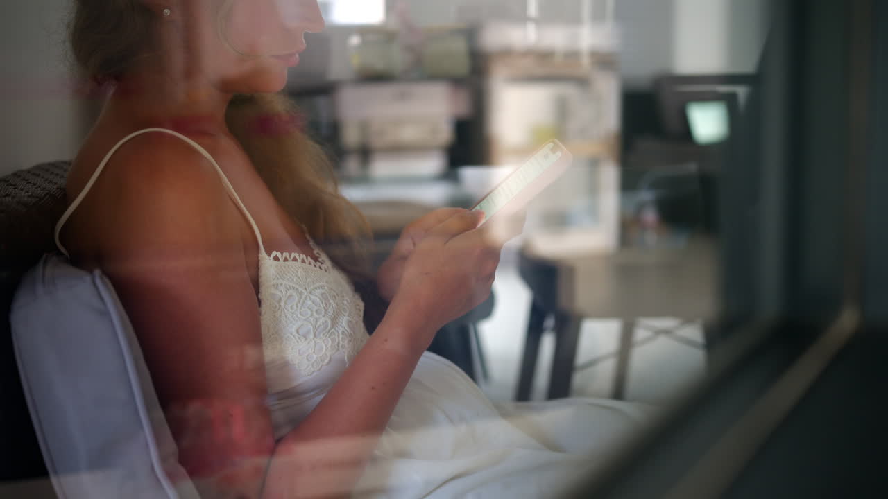 Woman in a white dress scrolling on her phone