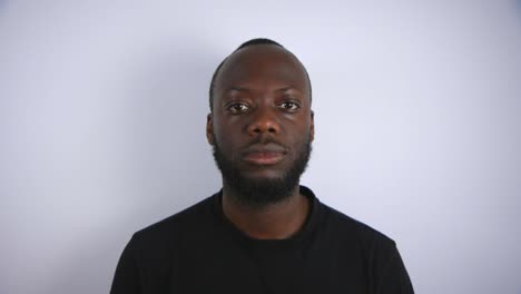 black male staring into camera with a blank face with white background