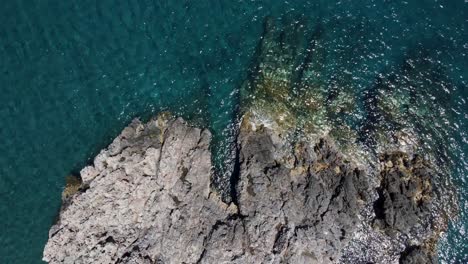 rising aerial top view over mediterranean seashore rocks and blue waters