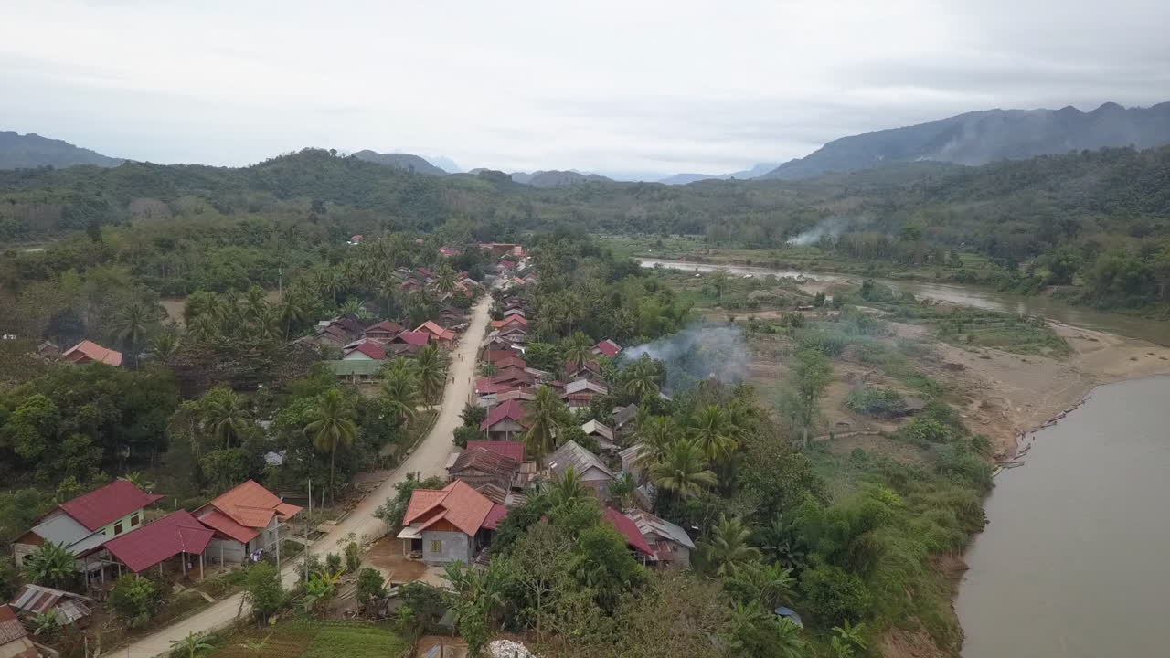 moscas aéreas a baja altura sobre el pueblo del río en la jungla montañosa del norte de laos