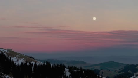 Faszinierende-Luftaufnahme,-Die-Das-Erste-Licht-Des-Sonnenaufgangs-über-Der-Silhouette-Einer-Schneebedeckten-Bergkette-Einfängt,-Gefilmt-Mit-Einer-Drohne