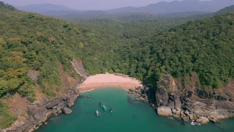 a breathtaking aerial drone view of butterfly beach in goa, india, with golden sands, calm waters, dense forests and boats floats near the shore