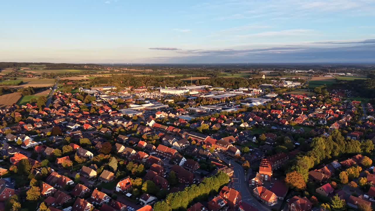 Red brick houses and homes with colored trees in autumn season. Sunset time with agricultural farm fields in background. Aerial rising wide shot. Peaceful and quaint neighborhood