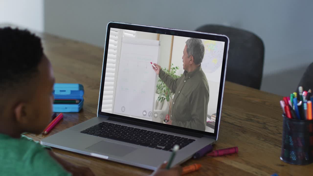 African american boy having a video call on laptop while doing homework at home