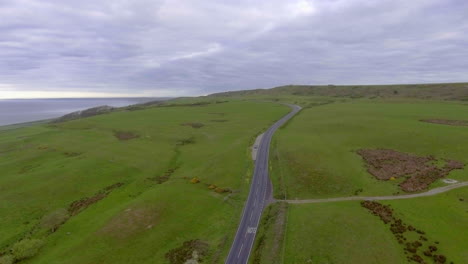aerial drone shot over a road in the countryside heading out to sea on the south coast of england in dorset