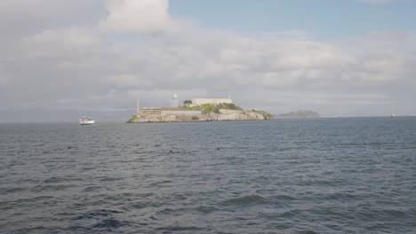 Isla-De-Alcatraz-En-La-Distancia-Con-Un-Barco-Navegando-Junto-A-Ella-Con-San-Francisco-Al-Fondo