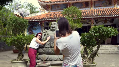 women are photographed near the buddha statue near the temple