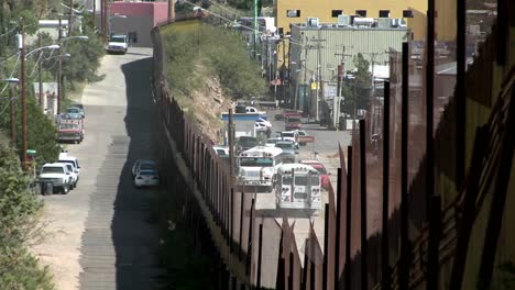 a border fence shows the separation of a community between a rural area and a densely populated area