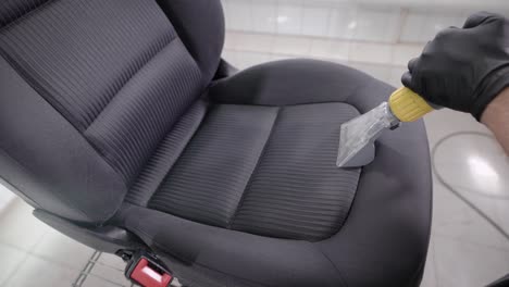 person cleaning folds of car seat