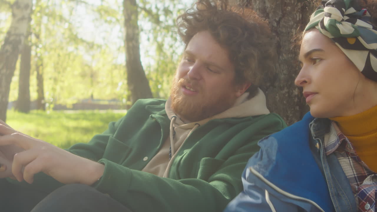 Young people relaxing and chatting in a sunny park