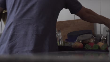 vista trasera de una persona secando vajilla lavada junto a frutas frescas en la cocina - plano medio