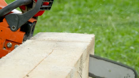 a worker cuts a wooden beam with a gasoline saw