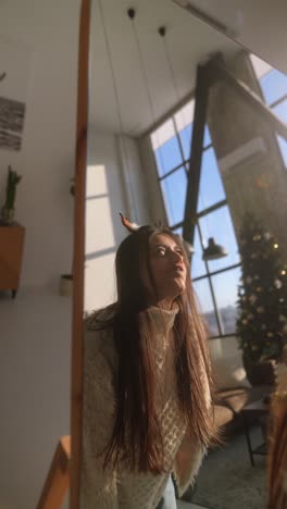 woman having fun with christmas antlers in front of a mirror