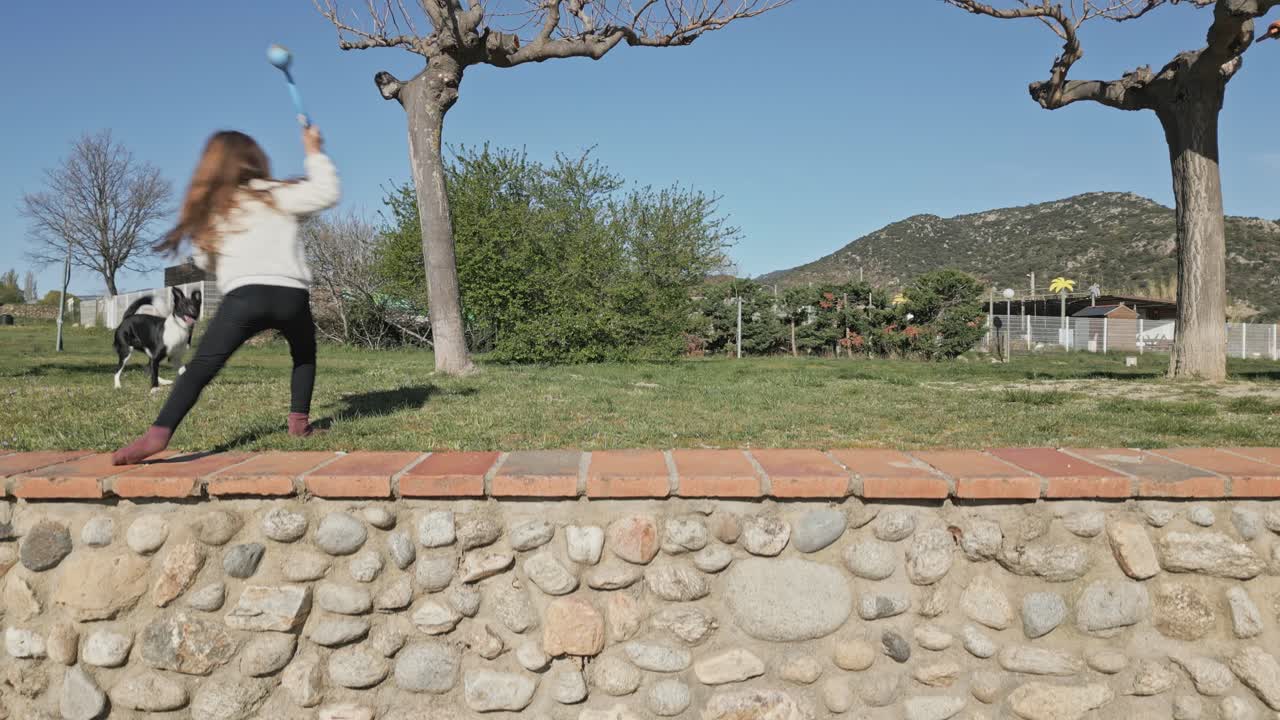 A Little Blonde Girl's Dog is Fetching the Ball, Playing at the Countryside Valley of Lac Vinça, France, Pyrenees Landscape, Aerial Drone Shot