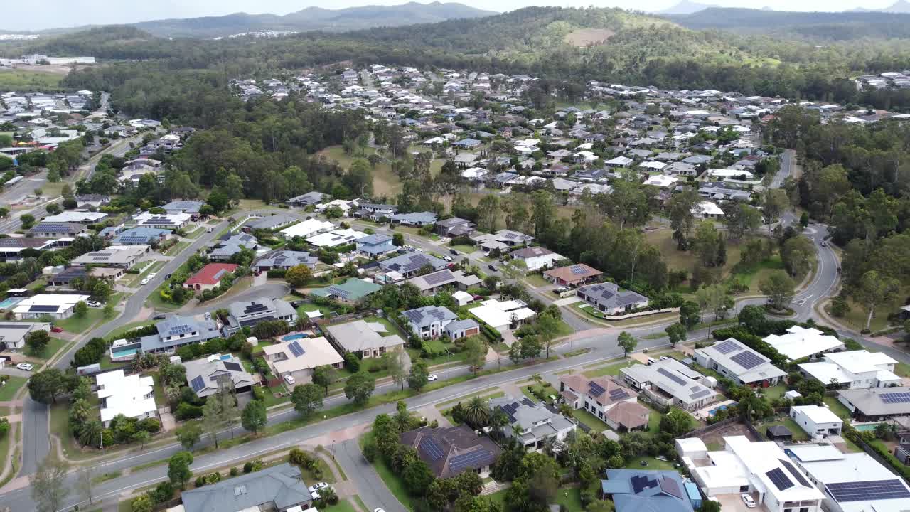 vista aérea de un barrio australiano con densas casas privadas y una tranquila calle suburbana y una franja verde