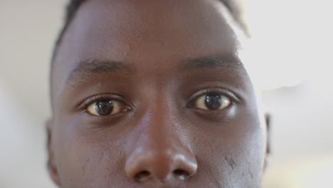 Eyes-of-happy-african-american-man-laughing-in-sunny-living-room,-slow-motion