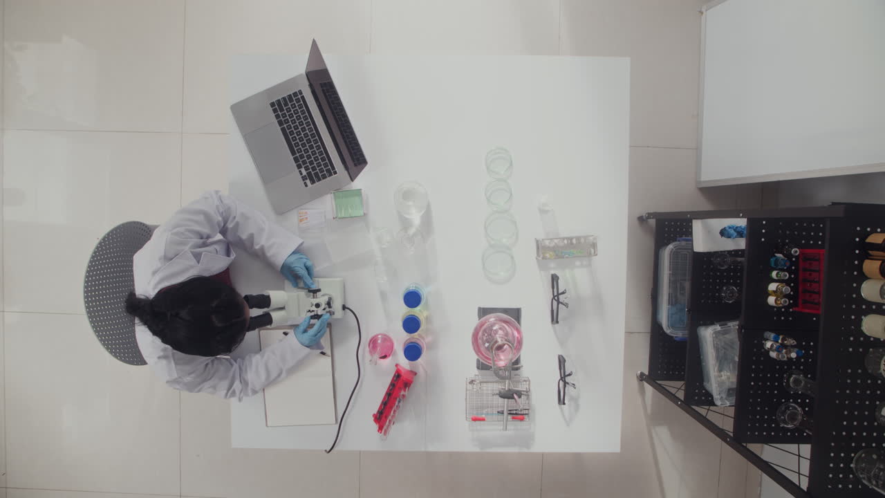 Female Laboratory Specialist Working with Microscope