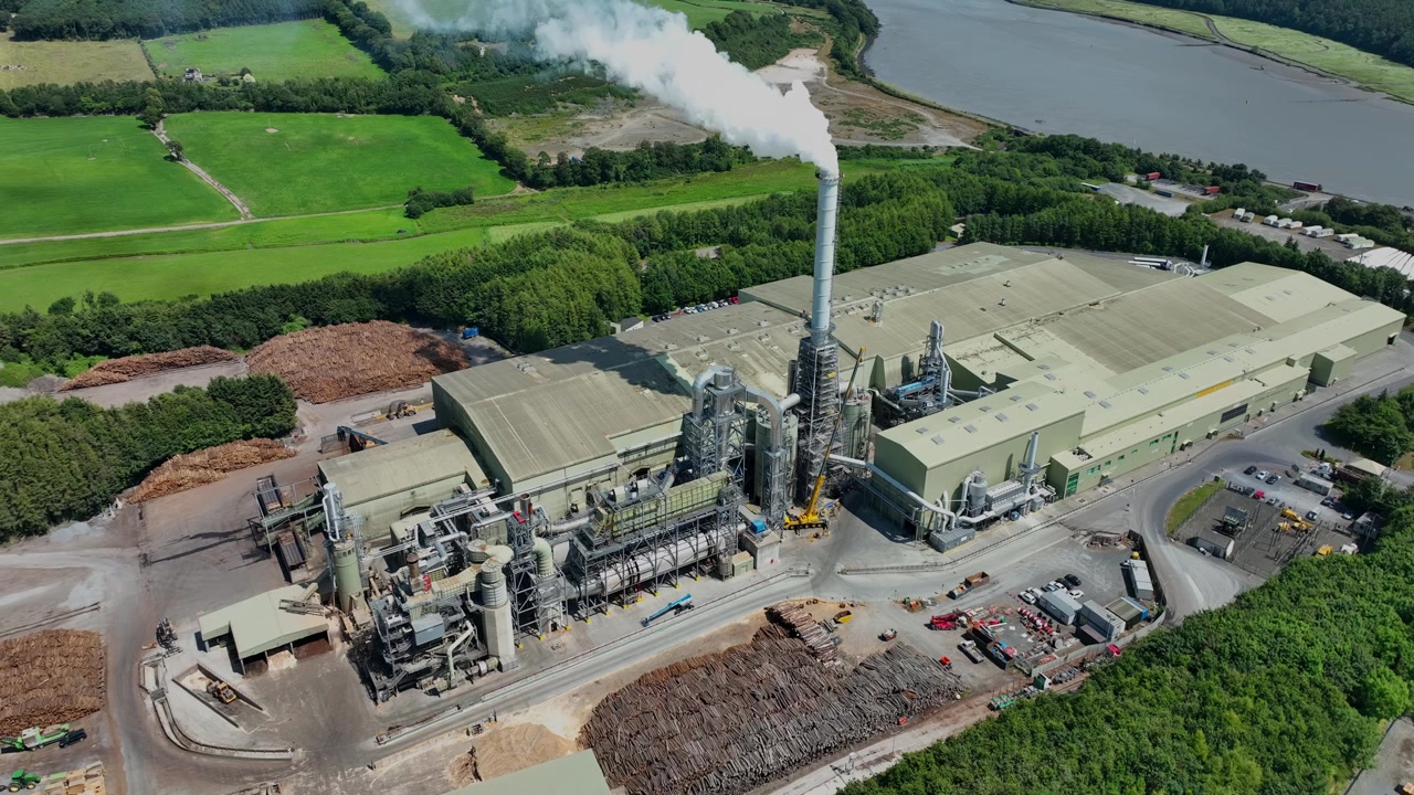 Aerial view of wood processing plant next to Suir River Waterford Ireland stock of logs and steam emitting from chimney on a summer day in Ireland