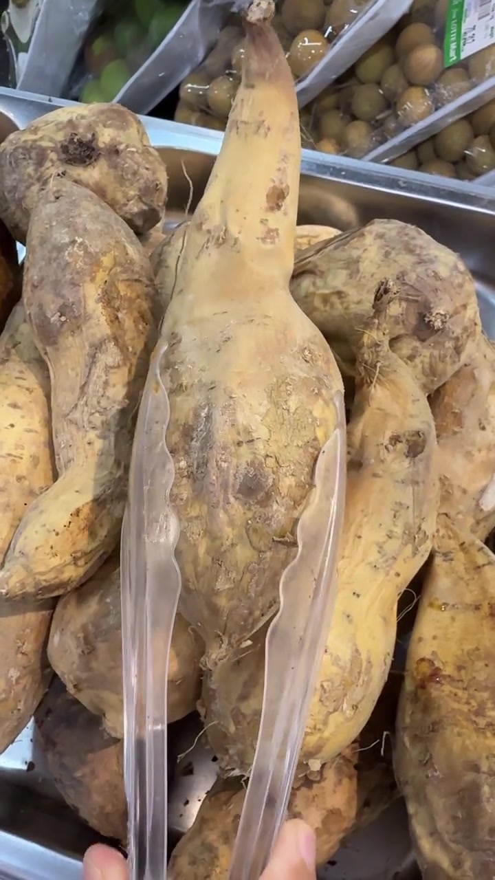 Persona che seleziona patate dolci fresche con le pinze al supermercato