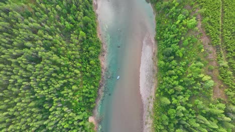 rafters on shallow river with riverbed exposed through evergreen forest in montana, usa