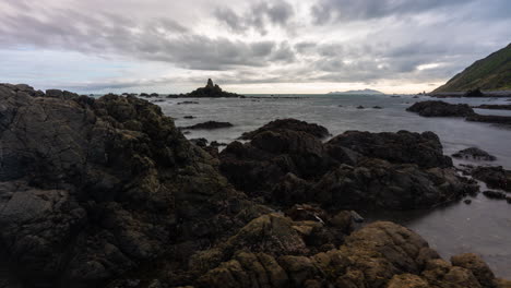 a time lapse of a rugged new zealand beach in the wellington region, panning from left to right on a slider with moving clouds