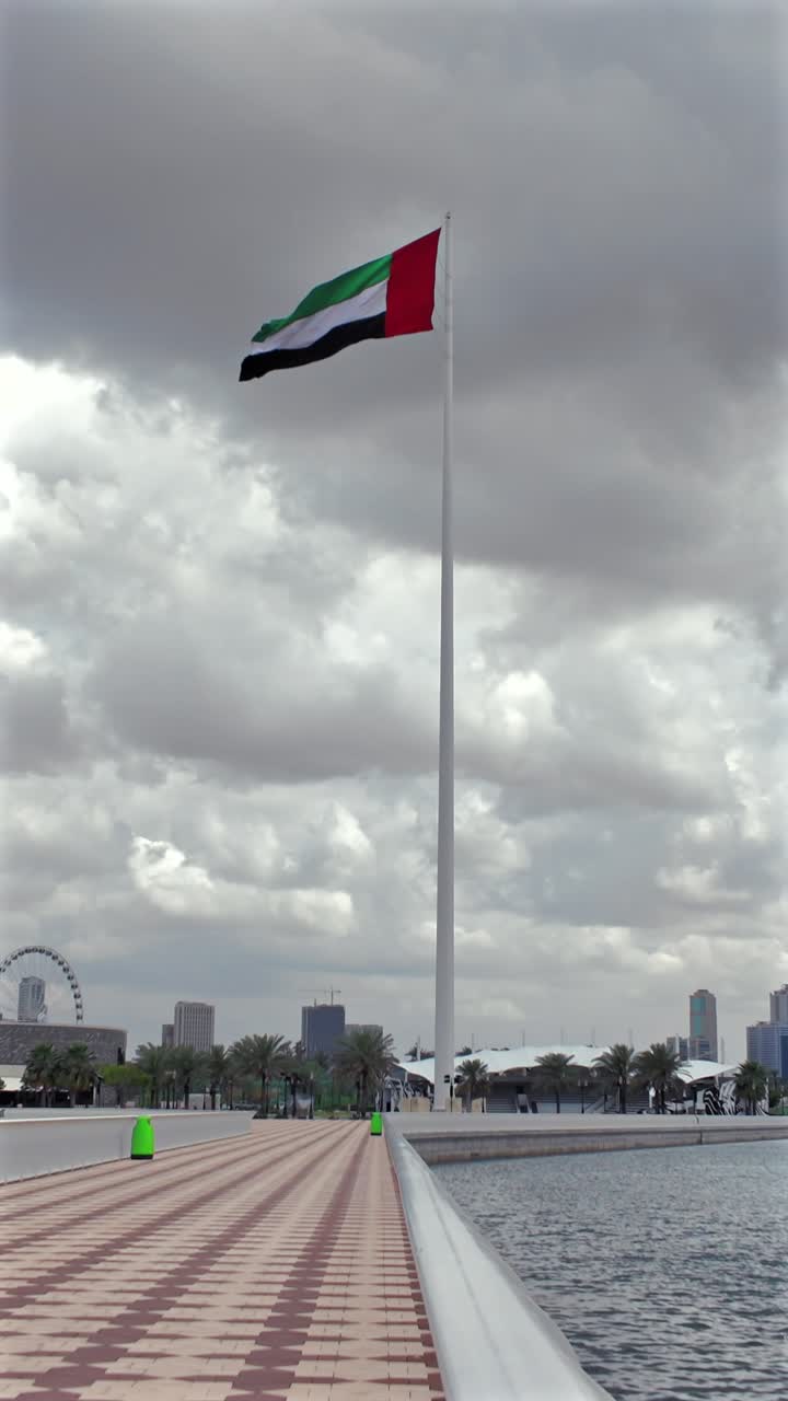 Bulutlu bir günde Sharjah üzerinde dalgalanan BAE bayrağının görünümü.