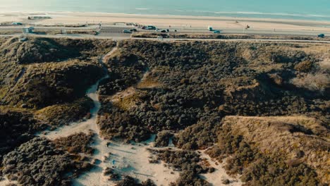 El-Ojo-De-Pájaro-Aéreo-Sobre-El-Terreno-De-Las-Dunas-De-Arena-Se-Inclina-Hacia-El-Horizonte-De-La-Carretera-Costera-Del-Océano