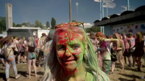 young happy girl in colourful powder is jumping and shaking head on holi festival in daytime in summer, color concept