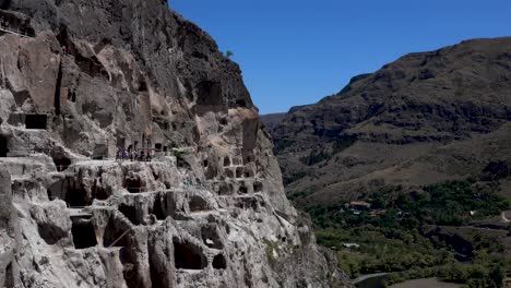 Colorful-group-of-tourists-visiting-impressive-cave-monastery-Vardsia-in-Georgia