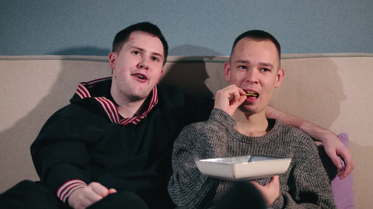 두 남자가 집에서 영화를 보고 있다.