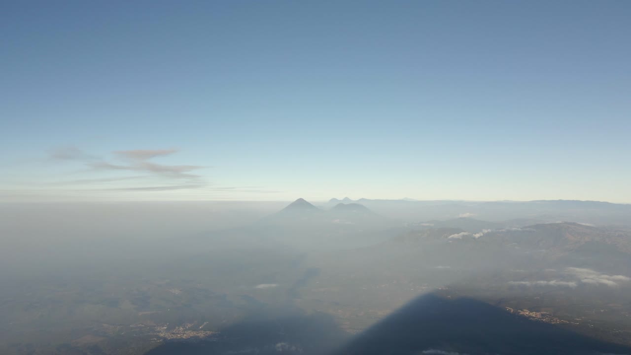 Panoramic overview of misty haze spreading below Volcano Fuego sunlit landscape sprawling out to horizon