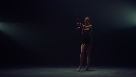 flexible woman training with maces. professional gymnast performing indoors.