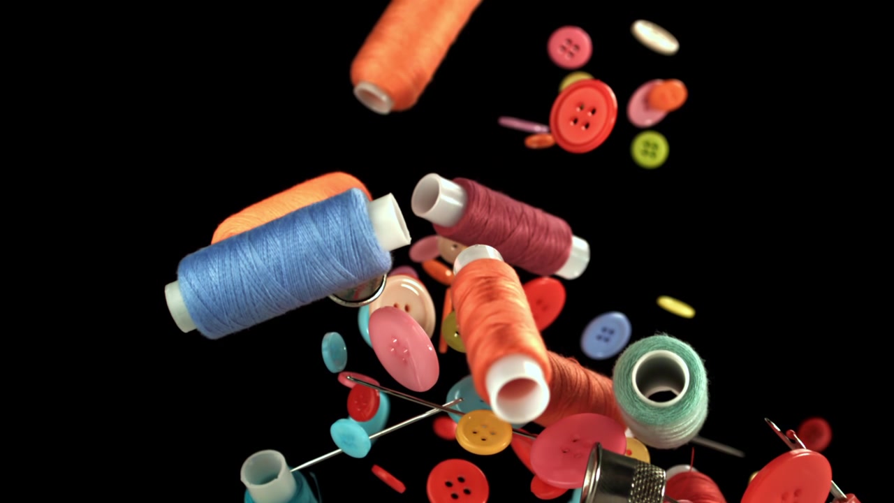 Vibrant Sewing Threads and Buttons Falling on Black Background