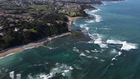 Aerial-View-of-French-Basque-Country-Coastline-close-to-Biarritz,-France-with-ocean-waves-breaking-on-reefs-and-beachside-homes-in-the-countryside