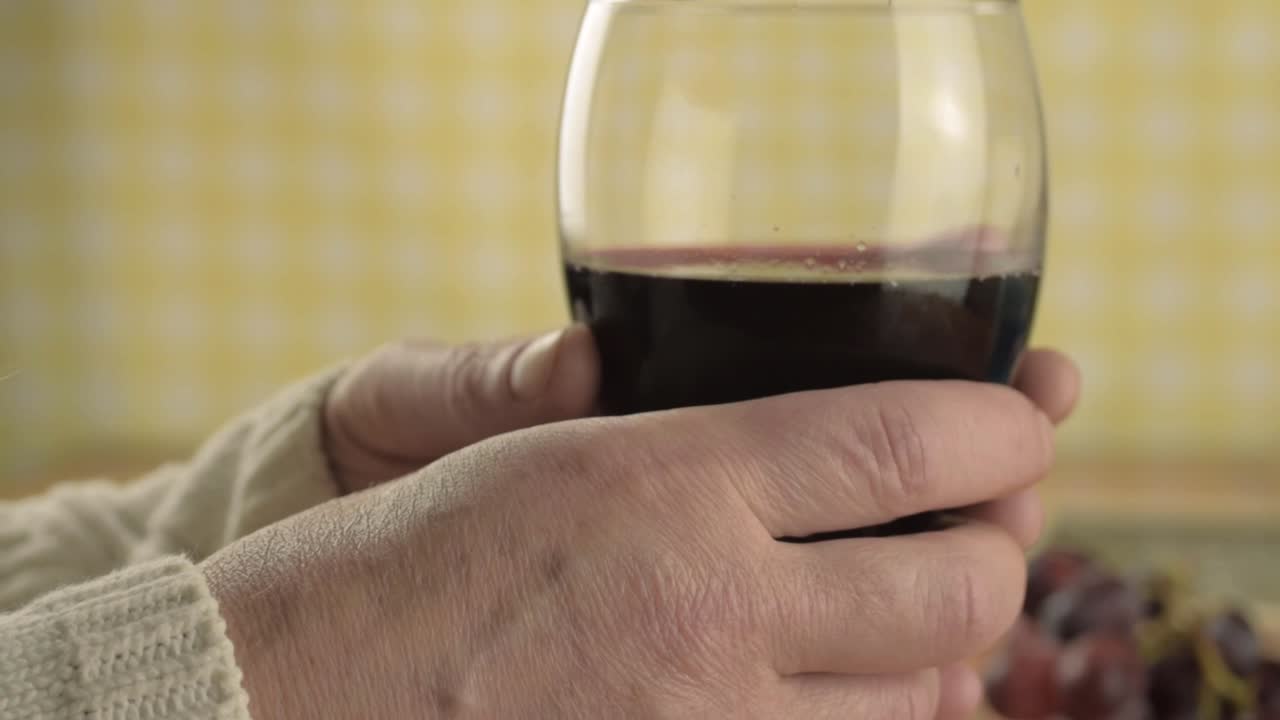 Hands holding glass of red wine close up shot
