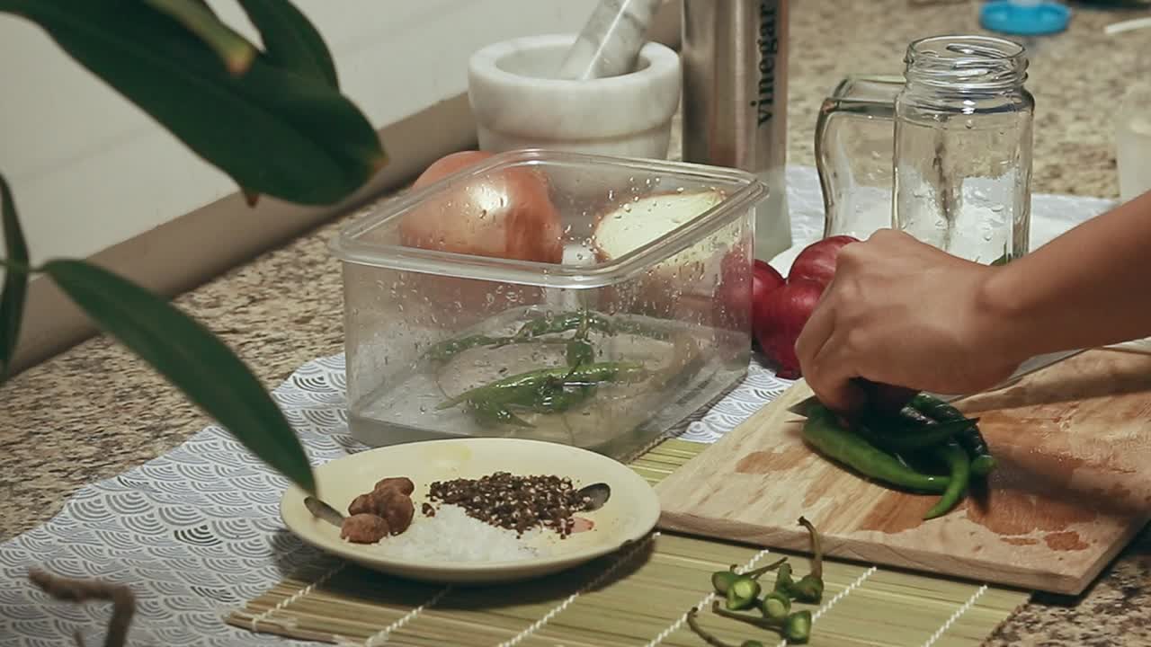 Chopping green chillies and putting them in a glass jar for a vinegar pickled chilli recipe. Healthy sustainable slow living lifestyle