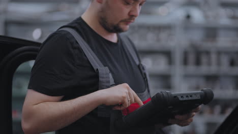 using digital tablet for a car diagnostic. mechanic using a tablet pc at the repair garage service. interactive diagnostics software on an computer.