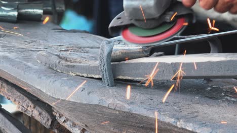 primer plano de una amoladora angular que muele una herramienta de metal en un taller