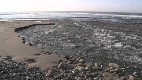 water flowing out of the ventura river estuary at surfers point in ventura california