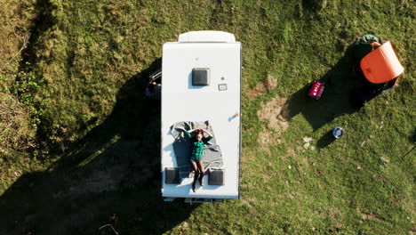 Vista-Superior-Desde-El-Dron-De-Una-Hermosa-Joven-Relajándose-Encima-De-Una-Autocaravana