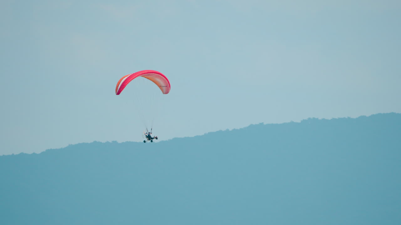 Motorized Hang Glider Flying Against Mountains Landscape - Tracking Motion