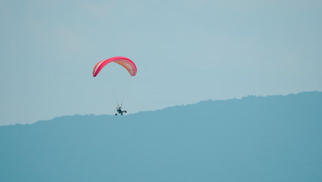 motorized hang glider flying against mountains landscape - tracking motion