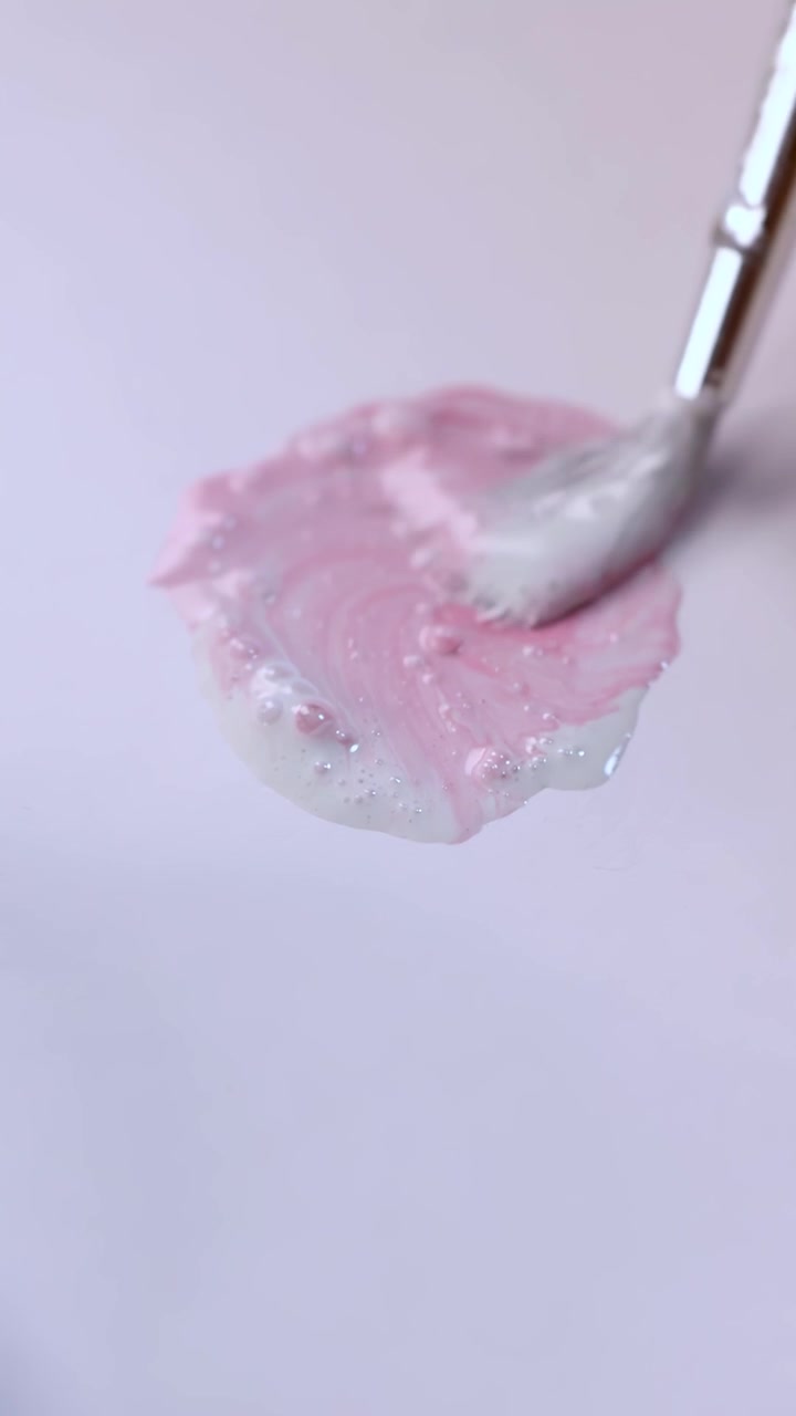 Artist mixes pink paint with brush on palette, soft lighting, macro close-up, smooth camera movement