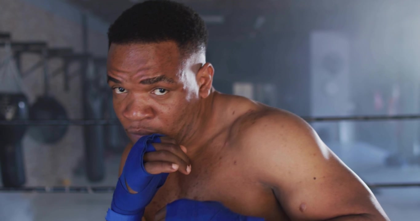 Boxer wearing blue wraps delivering left jab scattering neon letters landing right cross in fitness