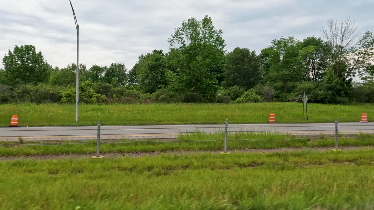 Dolly in moving car capturing side view from window on busy two-way road.