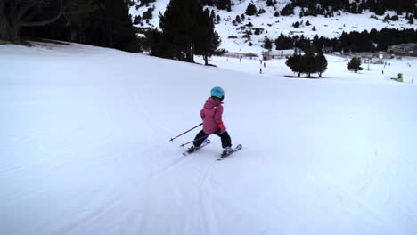 Slow-motion-rear-view-child-learning-to-ski-downhill-on-snowy-Andorra-ski-resort-slope